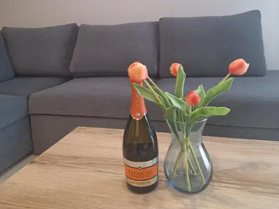 a bottle of wine and a vase of flowers on a table at Apartament N89 Wiślane Tarasy in Kraków