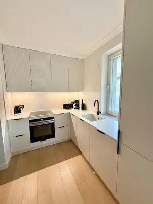 a kitchen with white cabinets and a sink and a window at Pearl of the city in Kraków