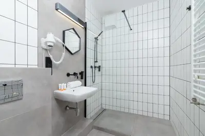a white tiled bathroom with a sink and a shower at Cracow Miodowa 42 Elegant Studios by Noclegi Renters in Kraków