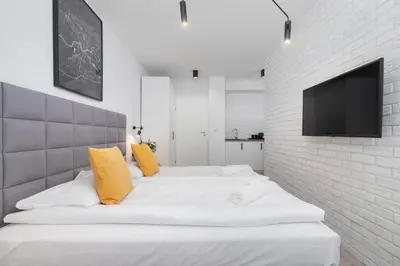 a bedroom with two white beds and a tv on a brick wall at Cracow Miodowa 42 Elegant Studios by Noclegi Renters in Kraków