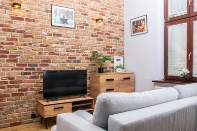 a living room with a brick wall and a television at TiB Apartament na Kazimierzu in Kraków