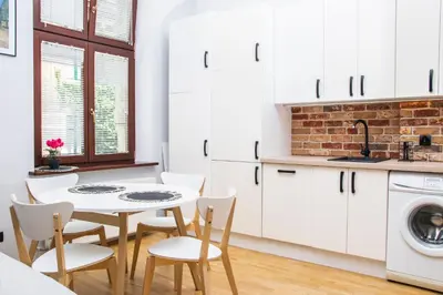 a kitchen with white cabinets and a table and chairs at TiB Apartament na Kazimierzu in Kraków