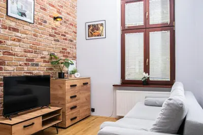 a living room with a tv and a brick wall at TiB Apartament na Kazimierzu in Kraków