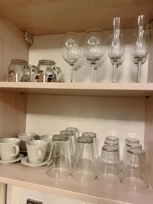 a row of wine glasses and bowls on a shelf at No̱410 City View Apartment & free private parking in Kraków