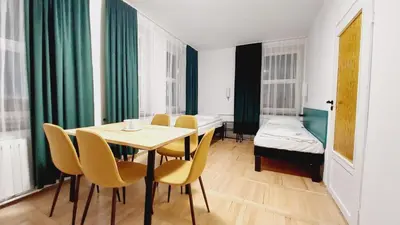 a dining room with a table and chairs and a bed at Korona Rooms in Kraków