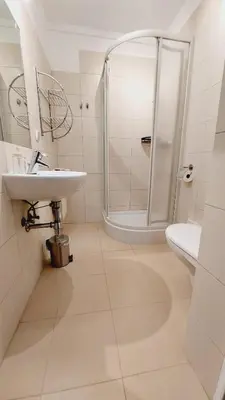 a white bathroom with a shower and a sink at Korona Rooms in Kraków