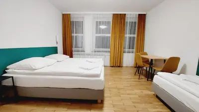 a hotel room with two beds and a table at Korona Rooms in Kraków