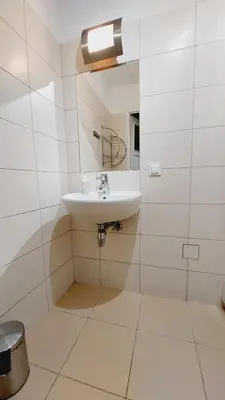 a white bathroom with a sink and a mirror at Korona Rooms in Kraków