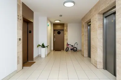 a hallway with white tile floors and a hallway with a bike at Cystersów Charming Apartment by BookingHost in Kraków