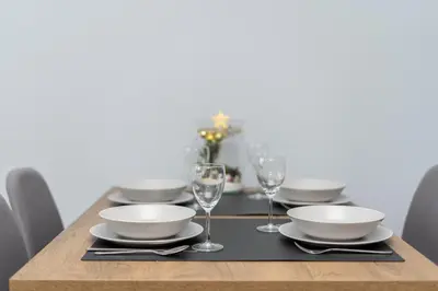 a wooden table with plates and glasses on it at Cystersów Charming Apartment by BookingHost in Kraków