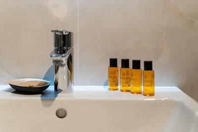 a white sink with four bottles of oils on it at Apartments Deluxe Cannes 51 by BookingHost in Kraków