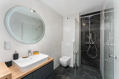 a bathroom with a sink and a shower with a mirror at Apartments Deluxe Cannes 51 by BookingHost in Kraków