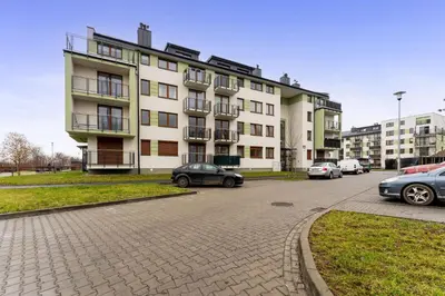 a large white building with cars parked in a parking lot at Apartments Deluxe Amsterdam 02 by BookingHost in Kraków