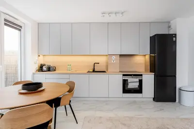 a kitchen with a wooden table and a black refrigerator at Apartments Deluxe Amsterdam 02 by BookingHost in Kraków