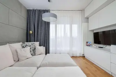 a living room with a white couch in front of a window at Lubicz Stylish Apartment with Parking and Air Conditioning in the City Center by Noclegi Renters in Kraków
