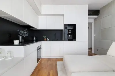 a white kitchen with white cabinets and a couch at Lubicz Stylish Apartment with Parking and Air Conditioning in the City Center by Noclegi Renters in Kraków