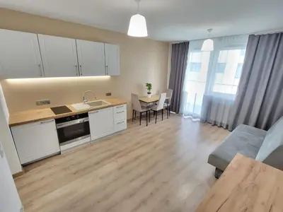 a kitchen with white cabinets and a table with chairs at Royal Smart Apartment in Kraków