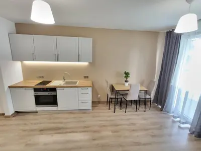 a kitchen with white cabinets and a table with chairs at Royal Smart Apartment in Kraków