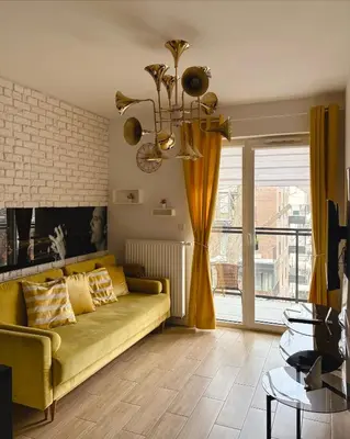 a living room with a yellow couch and a window at Apartamenty Figaretti Rakowicka in Kraków