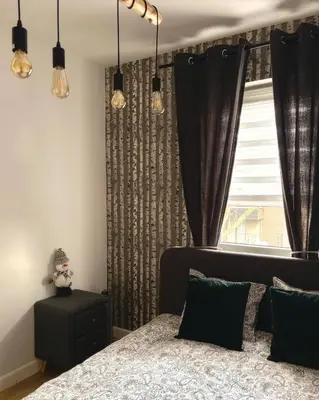 a bedroom with a bed with black curtains and a window at Apartamenty Figaretti Rakowicka in Kraków