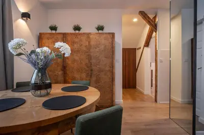 a dining room with a wooden table with flowers in a vase at Apartamenty Borek przy Modrej in Kraków