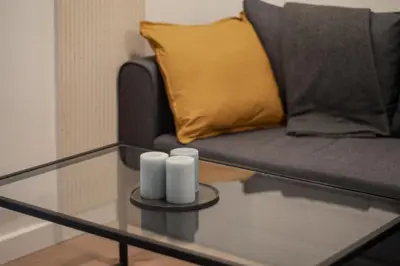 a glass coffee table with a couch and two white candles at Apartamenty Borek przy Modrej in Kraków