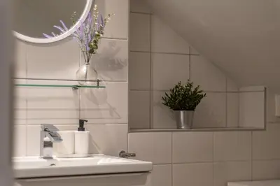 a bathroom sink with a mirror and a vase of flowers at Apartamenty Borek przy Modrej in Kraków