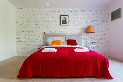 a red bed in a room with a brick wall at Pilotow 87 Apartments in Kraków
