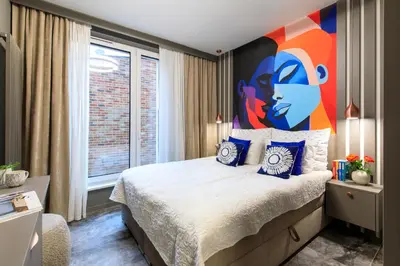 a bedroom with a bed with a large painting on the wall at Soho Residence in Kraków
