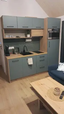 a kitchen with blue cabinets and a blue couch at Wiatrem Pisane in Roczyny