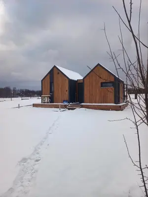 a couple of wooden buildings in the snow at Wiatrem Pisane in Roczyny