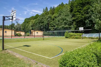 a tennis court with a net and a basketball hoop at Ponikiew Resort in Wadowice