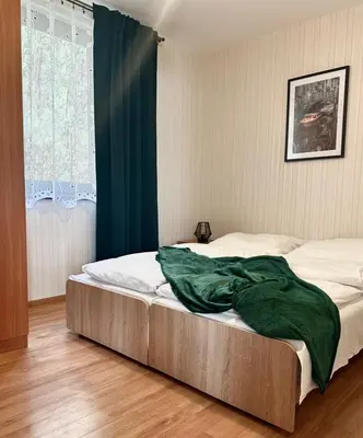 a bed with a green blanket on it in a bedroom at Ponikiew Resort in Wadowice