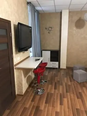 a room with a desk with a television and a red stool at Topolowa, studio-flat ground floor in Kraków