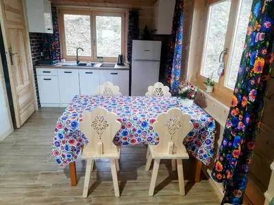 a kitchen with a table with chairs and a refrigerator at Domek na Przełęczy 2 in Wierzbanowa