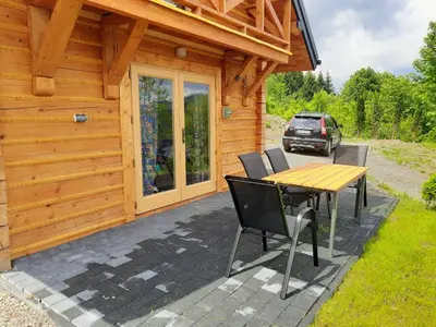 a wooden cabin with a table and chairs on a patio at Domek na Przełęczy 2 in Wierzbanowa