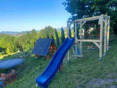 a playground with a blue slide and a house at Domek na Przełęczy 2 in Wierzbanowa