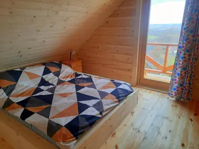 a bed in a wooden room with a large window at Domek na Przełęczy 2 in Wierzbanowa