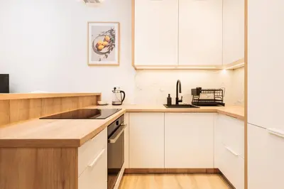 a kitchen with white cabinets and a sink at Kołłątaja Spacious Modern Apartment - by Upstairs in Kraków