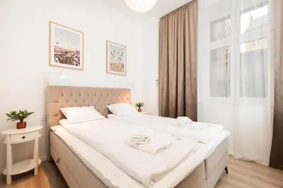 a bedroom with a bed with white sheets and a window at Kołłątaja Spacious Modern Apartment - by Upstairs in Kraków
