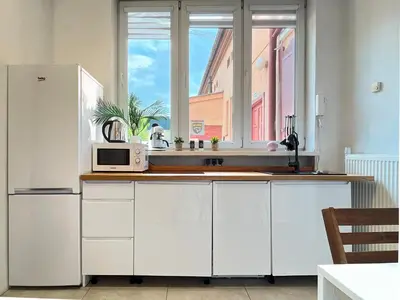 a white kitchen with a microwave and a window at Cozy Apartment for family next to Wawel & Old Town in Kraków