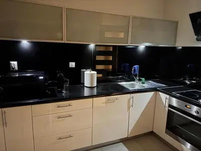 a kitchen with white cabinets and black counter tops at Apartament Bajeczny 87 - 5 min to Tauron Arena Cracow - beside the Vistula River in Kraków