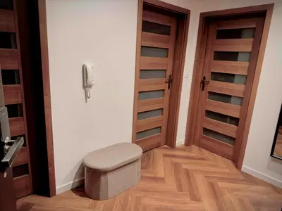 a room with two wooden doors and a stool at Apartament Bajeczny 87 - 5 min to Tauron Arena Cracow - beside the Vistula River in Kraków