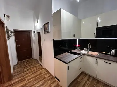 a kitchen with white cabinets and a black counter top at Old Cracow Apartment I in Kraków