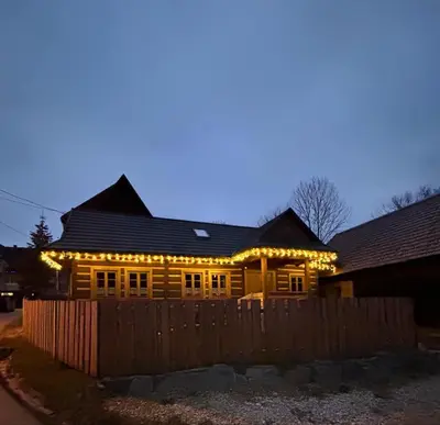 a wooden house with christmas lights on it at Domek Sidzina in Sidzina
