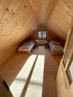an attic room with two beds and a window at Domek Sidzina in Sidzina