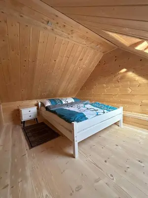 a bed in a attic with a wooden ceiling at Domek Sidzina in Sidzina