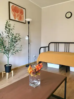 a room with two beds and a table with flowers on it at Apartament Łagiewniki 2 in Kraków
