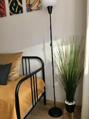 a black lamp next to a bed with a plant at Apartament Łagiewniki 2 in Kraków