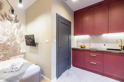 a small kitchen with red cabinets and a door at Apartamenty Limanowskiego in Kraków